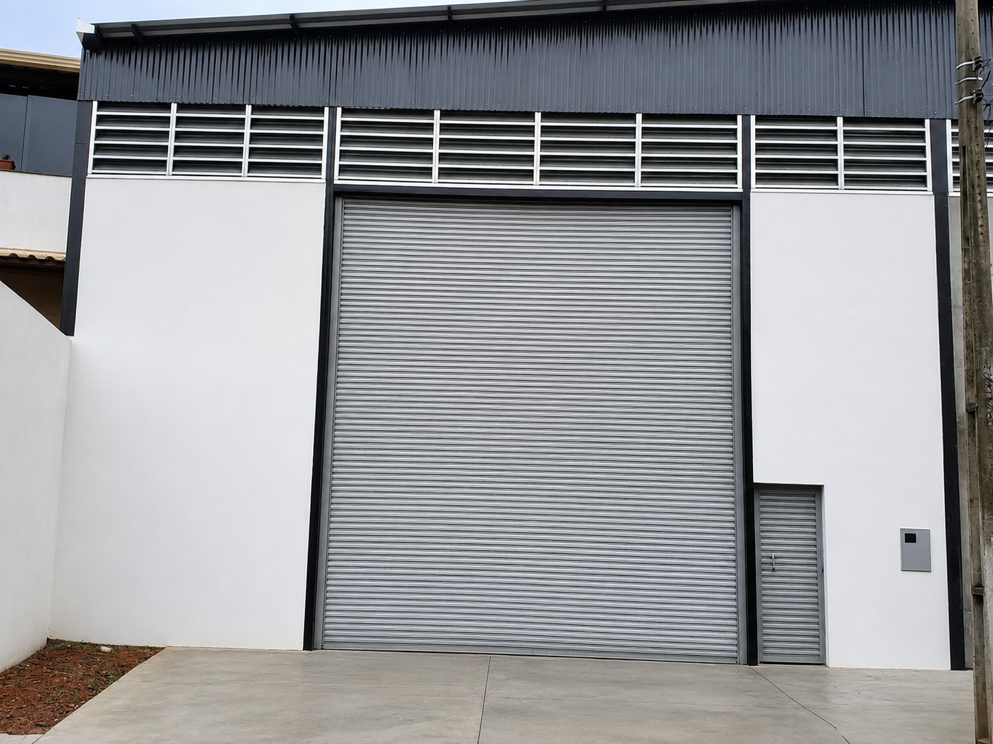 Fachada do galpão em Betim com porta automática de 5,61 x 4,80 metros no bairro Monte Verde