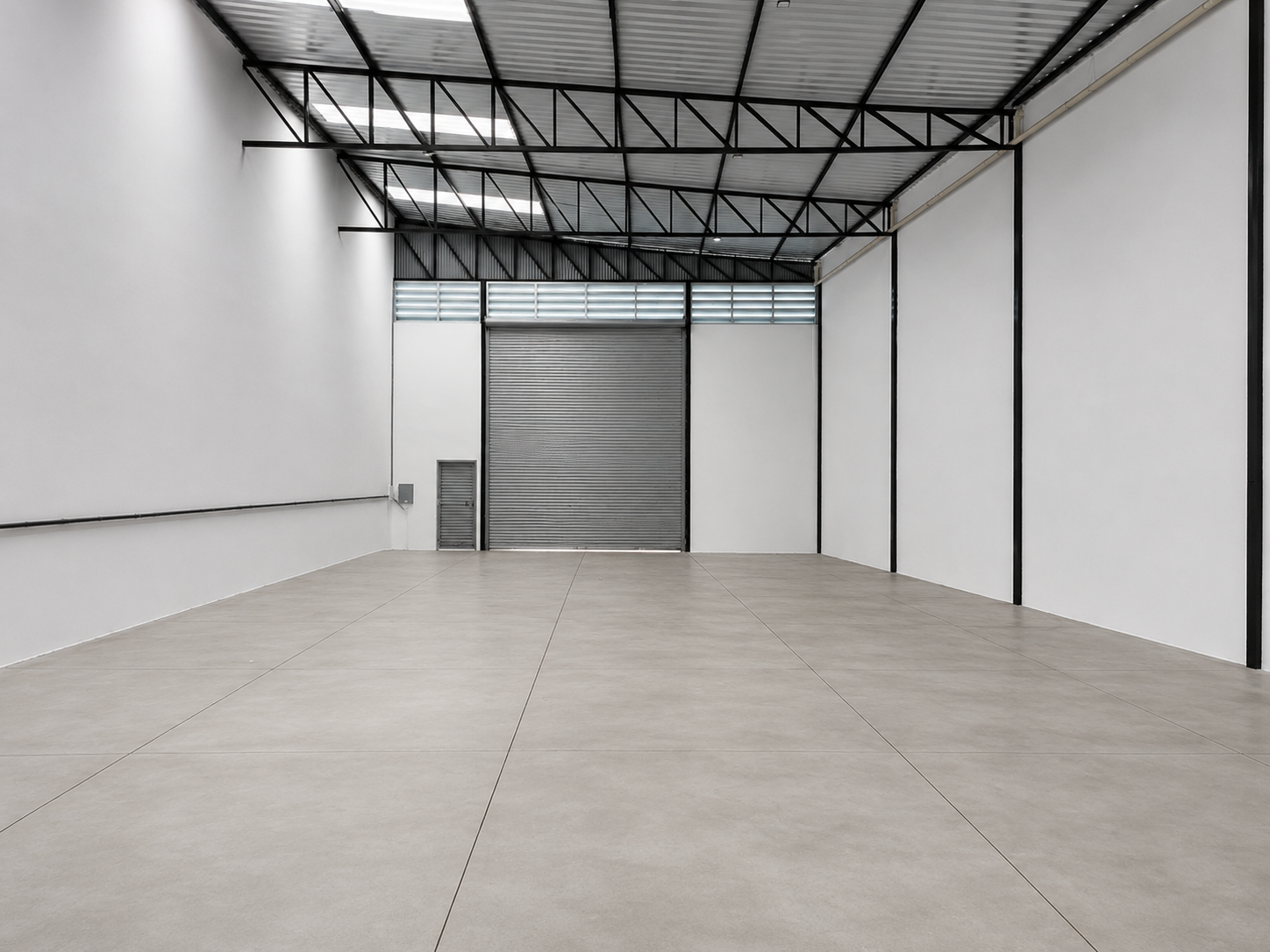 Área de armazenamento de 380 m² com porta automática ao fundo e estrutura metálica aparente