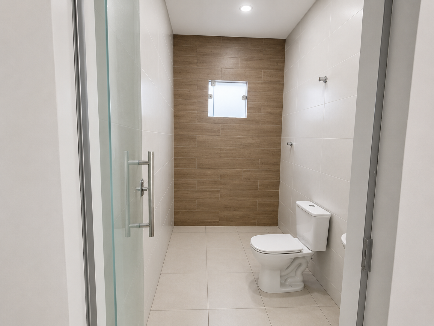 Banheiro com acabamento diferenciado em porcelanato e porta de vidro no galpão de Betim