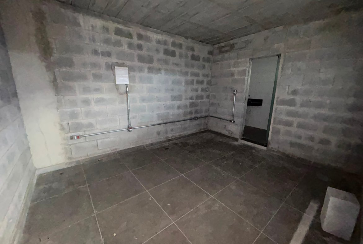 Sala do escritório do galpão em Petrolândia, com piso cerâmico e quadro de energia na parede