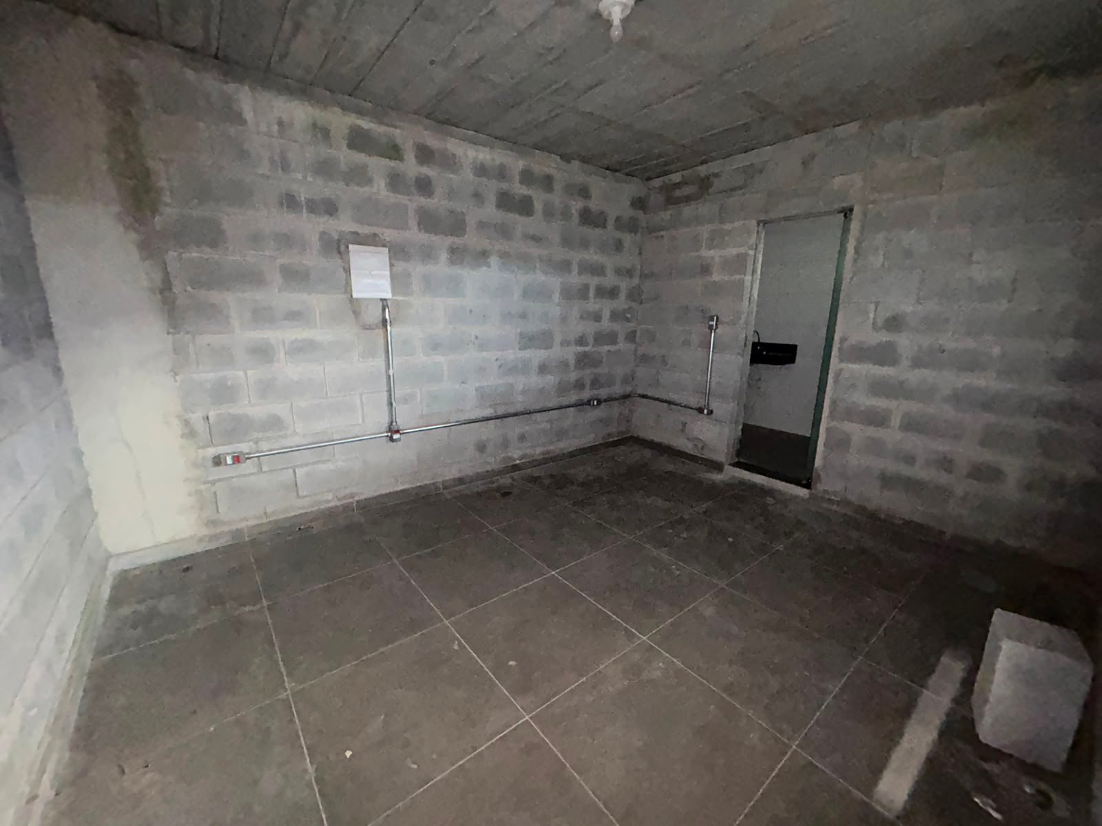Sala do escritório do galpão em Petrolândia, com piso cerâmico e quadro de energia na parede