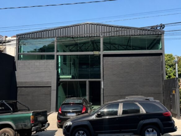 Fachada do galpão para locação no Riacho das Pedras, Contagem, com estrutura preta, fechamento em vidro e portão automático