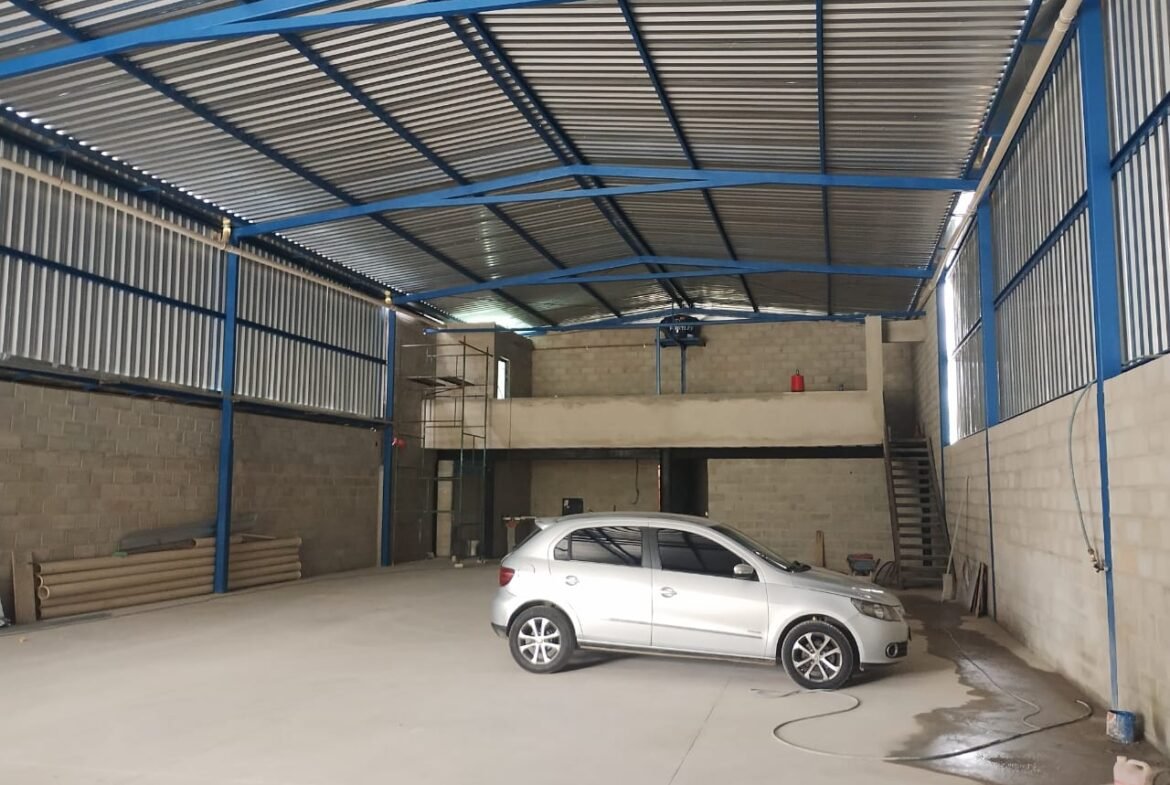 Interior do galpão com pé-direito de 6 metros e mezanino Interior do galpão de 420 m² com pé-direito de 6 metros, estrutura metálica e mezanino ao fundo, em Betim/MG