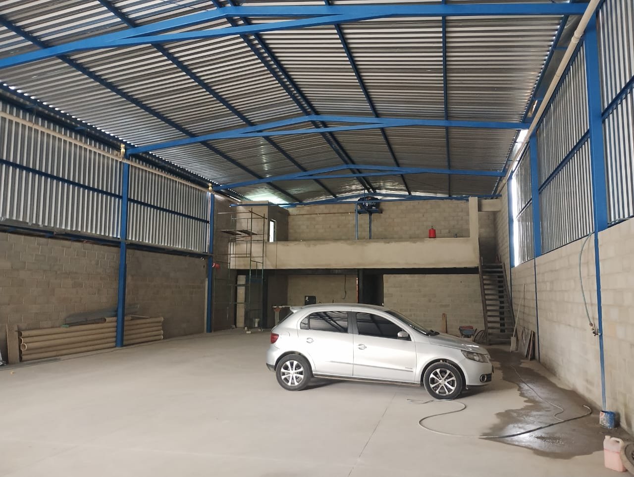 Interior do galpão com pé-direito de 6 metros e mezanino Interior do galpão de 420 m² com pé-direito de 6 metros, estrutura metálica e mezanino ao fundo, em Betim/MG