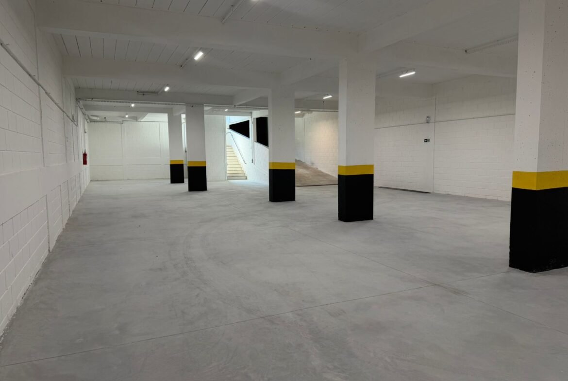 Subsolo de 360 m² do galpão em Contagem, com pé-direito livre, pilares sinalizados e iluminação em LED