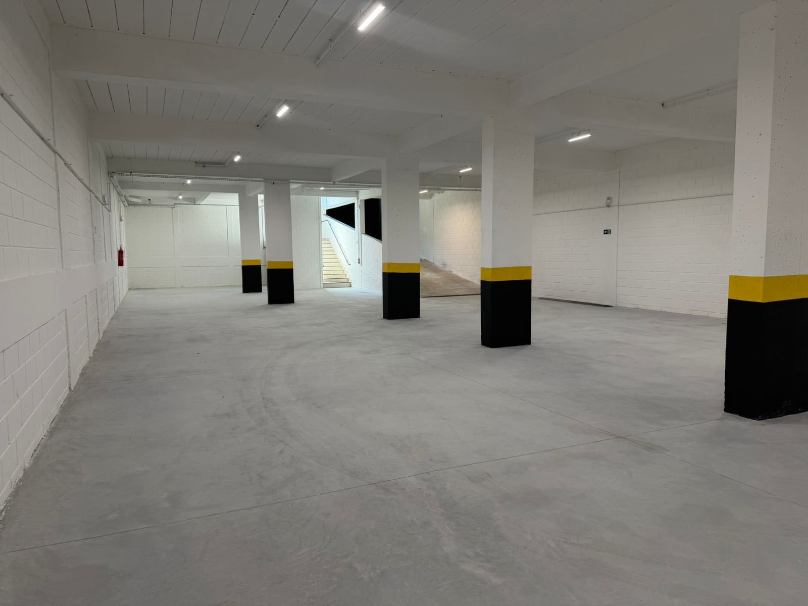 Subsolo de 360 m² do galpão em Contagem, com pé-direito livre, pilares sinalizados e iluminação em LED